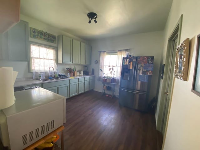 kitchen with a sink, light countertops, stainless steel fridge, and dark wood-style floors