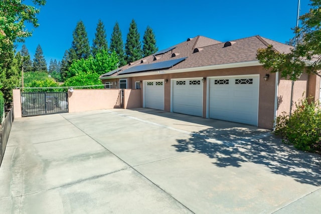 18778 Shore Dr, Madera, CA 93638 - view of property exterior featuring concrete driveway, stucco siding, an attached garage, a gate, and roof mounted solar panels