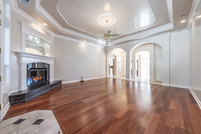 18778 Shore Dr, Madera, CA 93638 - unfurnished living room featuring a high end fireplace, ceiling fan, a tray ceiling, arched walkways, and wood-type flooring