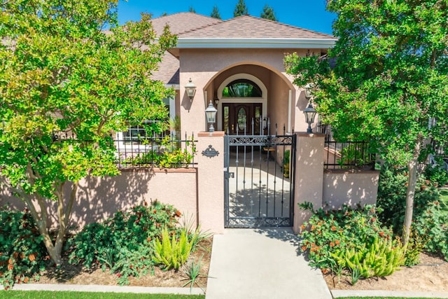 18778 Shore Dr, Madera, CA 93638 - view of exterior entry featuring fence, stucco siding, a gate, and roof with shingles