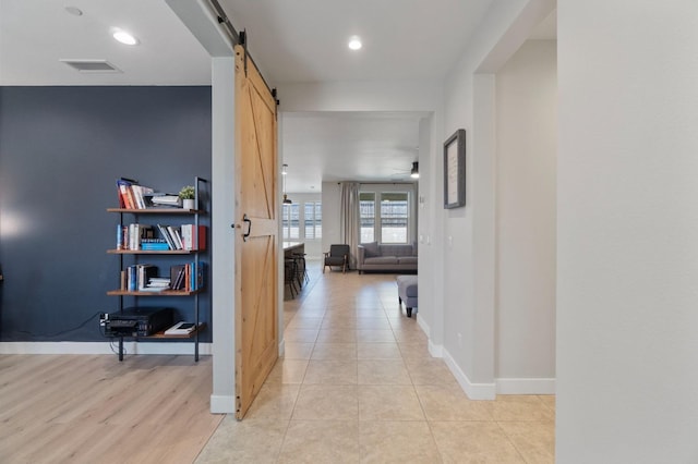 corridor featuring visible vents, baseboards, recessed lighting, and a barn door