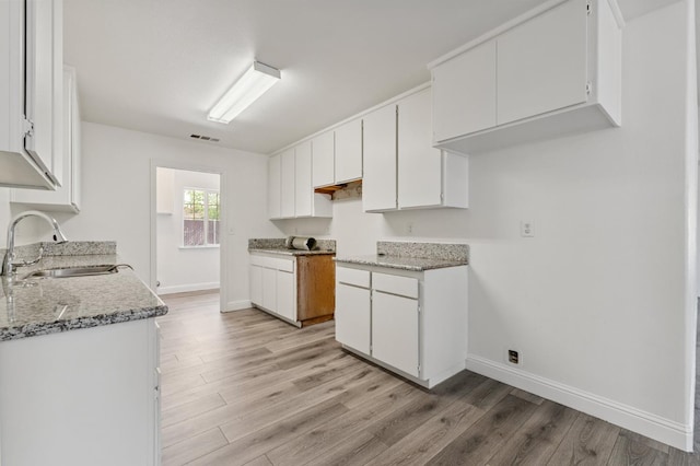 2464 S Kirk St, Fresno, CA 93706 - kitchen featuring light wood-style floors, white cabinets, and light stone countertops
