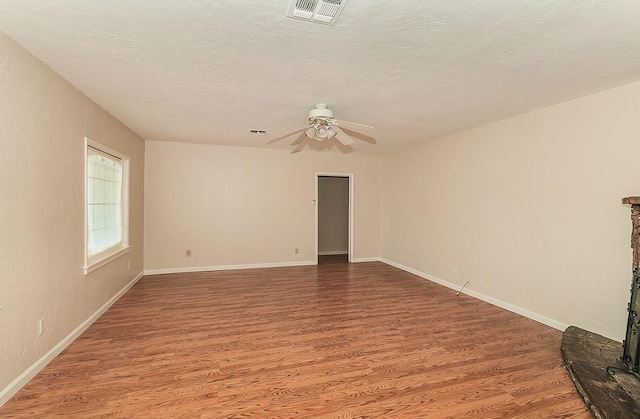 empty room with visible vents, baseboards, ceiling fan, a textured ceiling, and wood finished floors