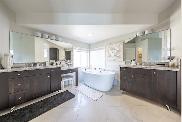 full bath with a freestanding tub, tile patterned flooring, and two vanities