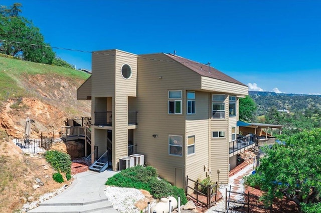 rear view of house featuring fence, cooling unit, and a balcony