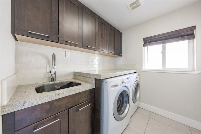 laundry room featuring baseboards, visible vents, independent washer and dryer, cabinet space, and a sink