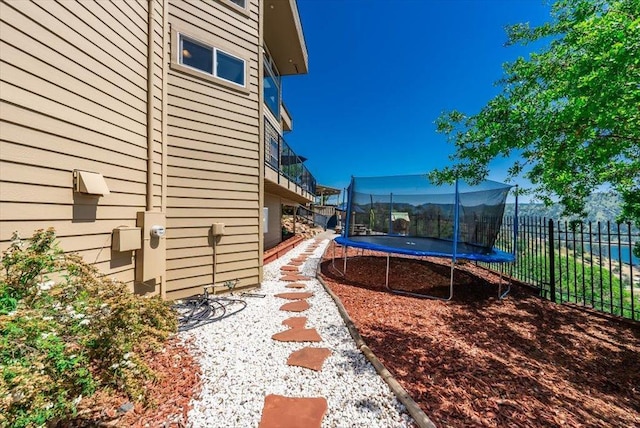 view of yard featuring a trampoline and fence