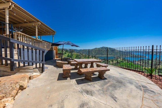 view of patio with a water view, fence, and outdoor dining space
