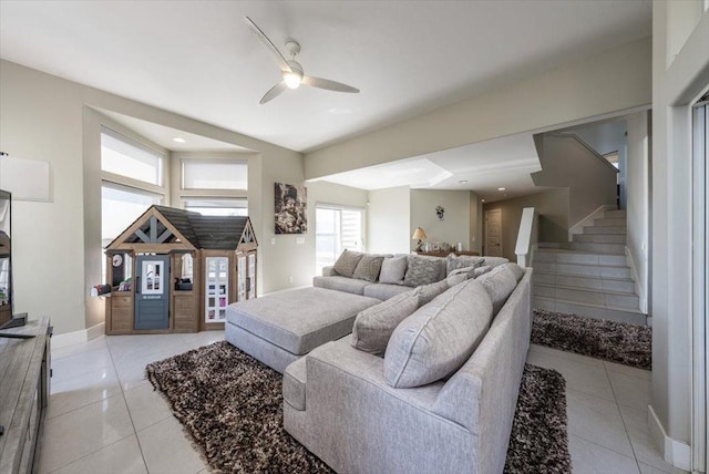 living room with ceiling fan, light tile patterned flooring, baseboards, and stairs
