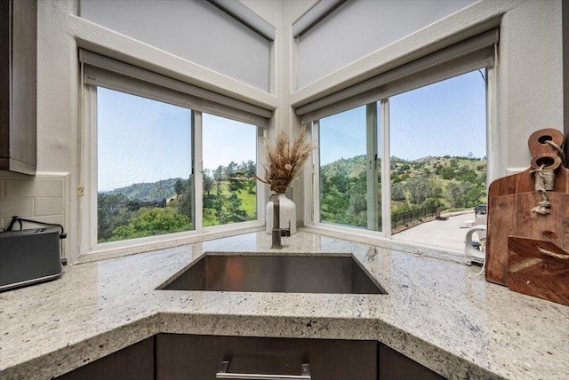 room details with a sink, a mountain view, decorative backsplash, and light stone counters
