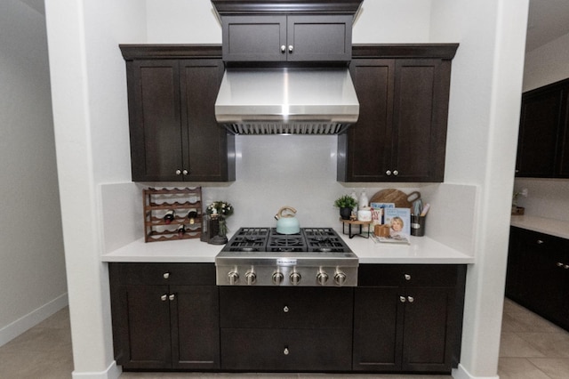 kitchen with stainless steel gas cooktop, wall chimney range hood, light countertops, and baseboards