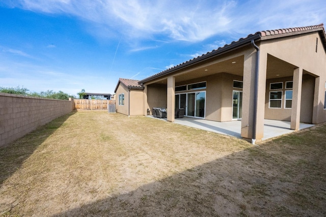 rear view of house featuring a tiled roof, a yard, a patio area, fence, and stucco siding