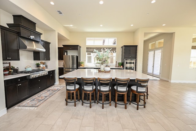 kitchen featuring range hood, light countertops, appliances with stainless steel finishes, and visible vents