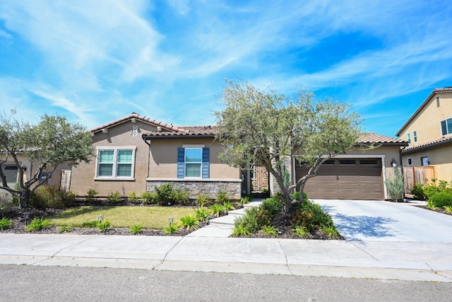 view of front of house featuring stucco siding, a front yard, a tile roof, a garage, and concrete driveway