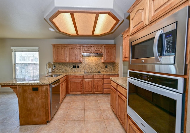10089 N Baird Ave, Fresno, CA 93730 - kitchen featuring a peninsula, appliances with stainless steel finishes, under cabinet range hood, a sink, and backsplash