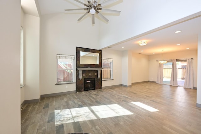 738 Century Ln, Clovis, CA 93612 - unfurnished living room with a tile fireplace, baseboards, ceiling fan with notable chandelier, and wood finished floors