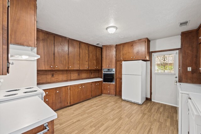 811 E Cambridge Ave, Fresno, CA 93704 - kitchen with white appliances, under cabinet range hood, brown cabinets, light wood-style flooring, and a textured ceiling