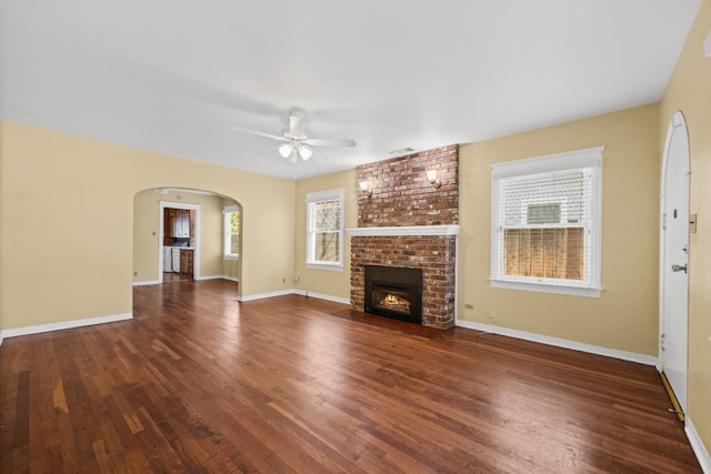 811 E Cambridge Ave, Fresno, CA 93704 - unfurnished living room with ceiling fan, a fireplace, wood finished floors, arched walkways, and baseboards