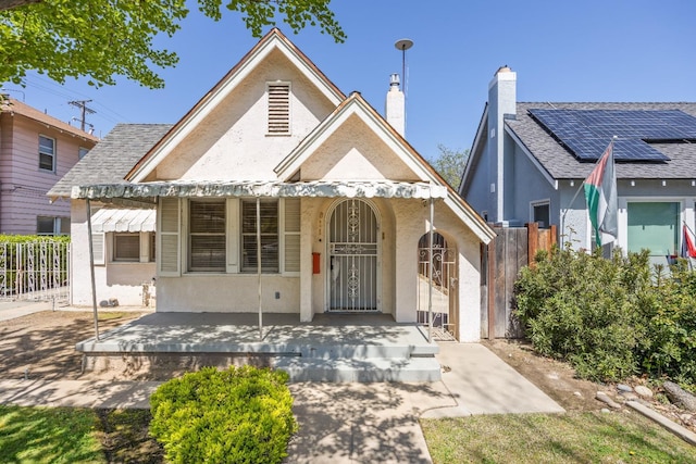 view of front of property with stucco siding, fence, a chimney, and covered porch