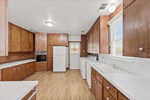811 E Cambridge Ave, Fresno, CA 93704 - kitchen featuring white appliances, washing machine and clothes dryer, a sink, brown cabinetry, and a textured ceiling