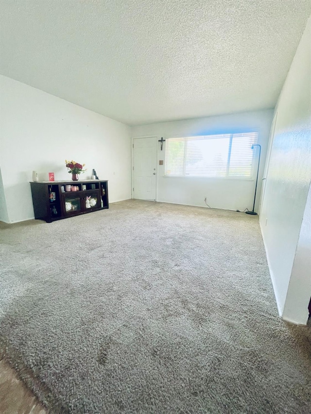 carpeted empty room with a textured ceiling