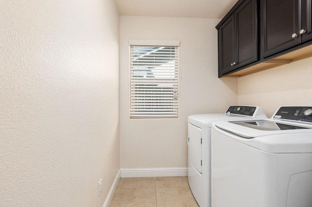 laundry area featuring light tile patterned flooring, washing machine and clothes dryer, baseboards, and cabinet space