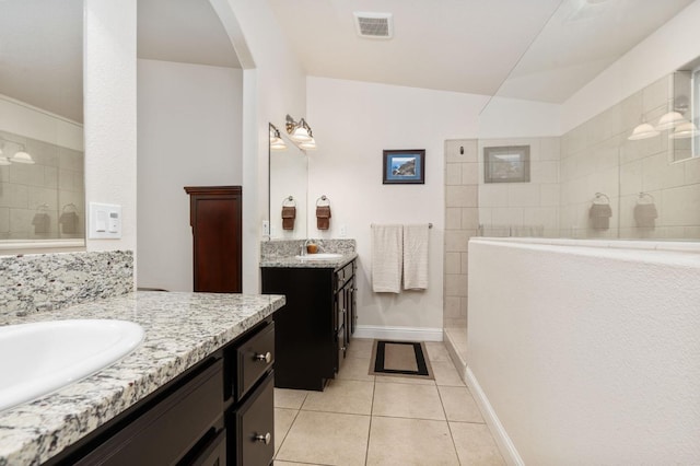 bathroom featuring two vanities, tile patterned flooring, walk in shower, visible vents, and a sink