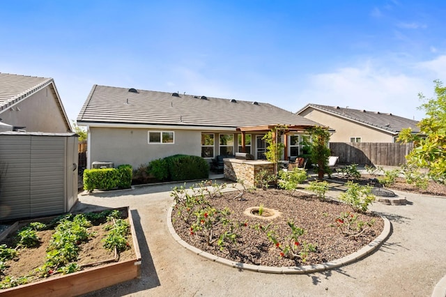 back of property featuring an outbuilding, a garden, a patio, a storage unit, and fence
