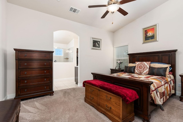 bedroom featuring visible vents, arched walkways, connected bathroom, light colored carpet, and lofted ceiling