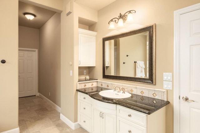 bathroom featuring baseboards, stone finish flooring, visible vents, and vanity