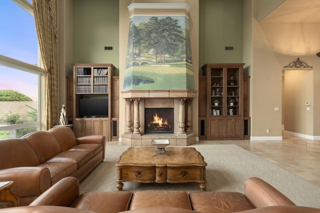 living room featuring visible vents, a high end fireplace, baseboards, and a high ceiling