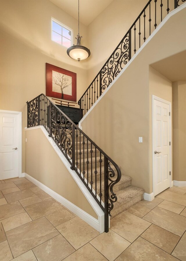 staircase featuring baseboards and a high ceiling