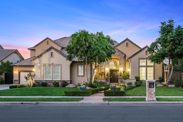 view of front of property featuring stucco siding, a front lawn, stone siding, and a garage