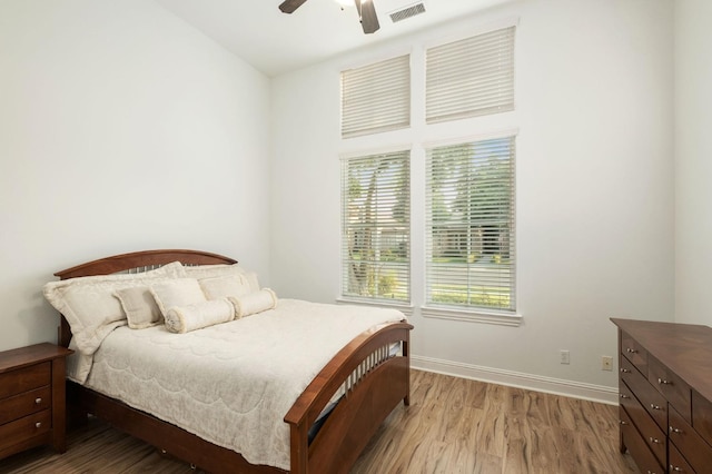 bedroom with visible vents, baseboards, wood finished floors, and multiple windows