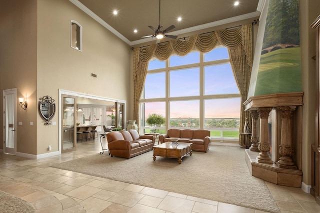 living room with a ceiling fan, a high ceiling, ornamental molding, and baseboards