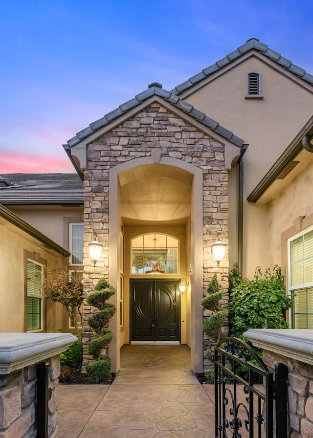 property entrance with stucco siding and stone siding