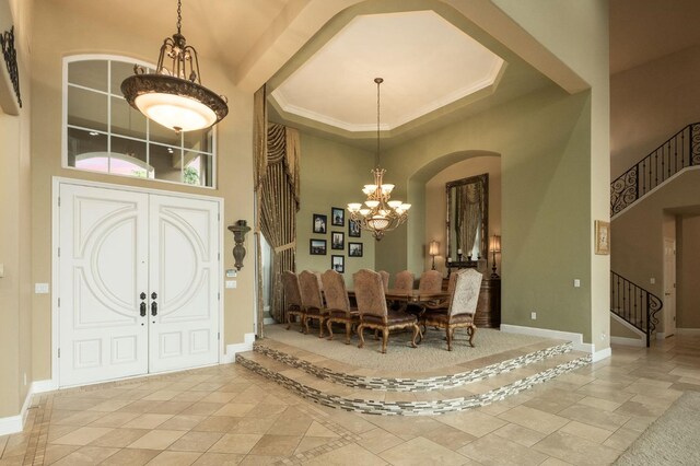 dining space featuring an inviting chandelier, arched walkways, baseboards, a towering ceiling, and stairway