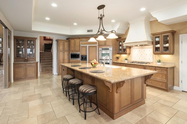 5136 W Bluff Ave, Fresno, CA 93722 - kitchen featuring brown cabinets, premium range hood, built in appliances, a kitchen breakfast bar, and decorative backsplash
