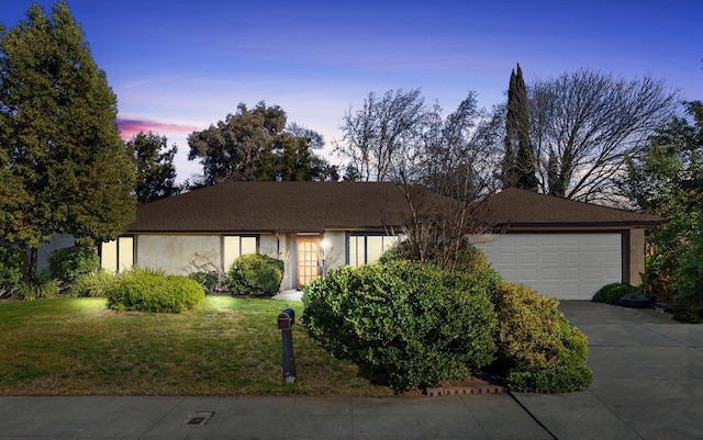 single story home with stucco siding, a garage, a lawn, and concrete driveway