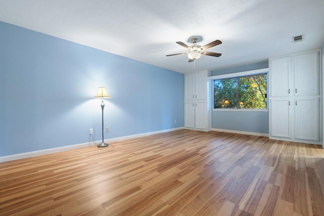 spare room featuring visible vents, light wood-type flooring, a ceiling fan, and baseboards