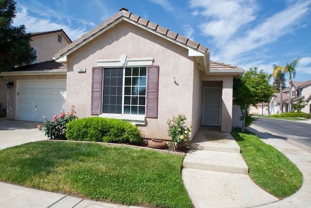 view of front of house featuring stucco siding, a tile roof, driveway, a front yard, and a garage