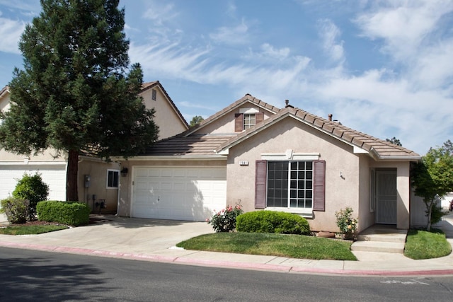 ranch-style home featuring an attached garage, a tile roof, driveway, and stucco siding
