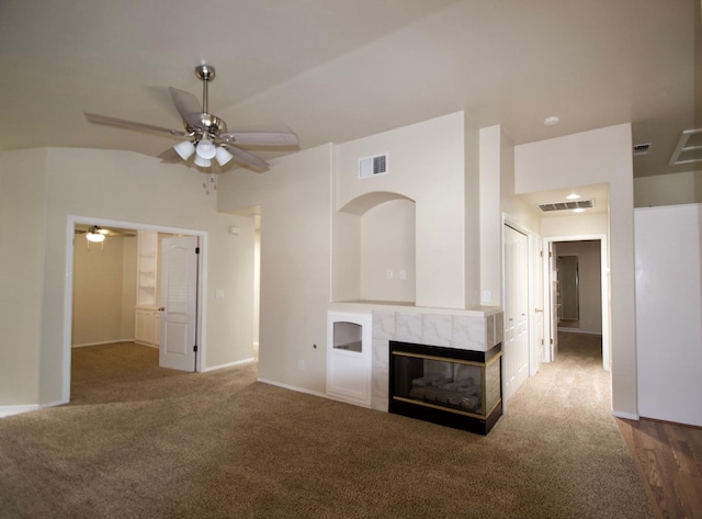 unfurnished living room featuring carpet, a ceiling fan, visible vents, and a fireplace