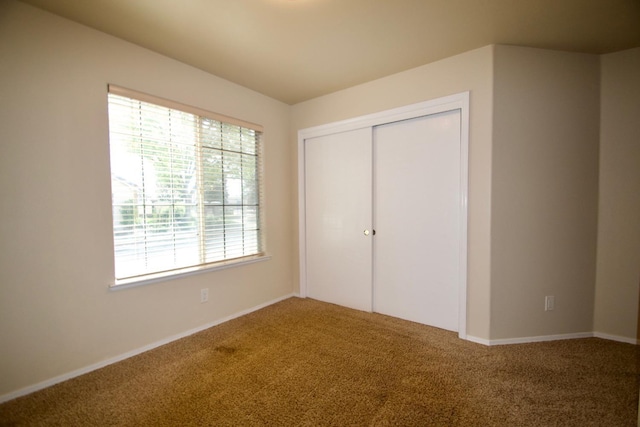 unfurnished bedroom with baseboards, carpet flooring, multiple windows, and a closet