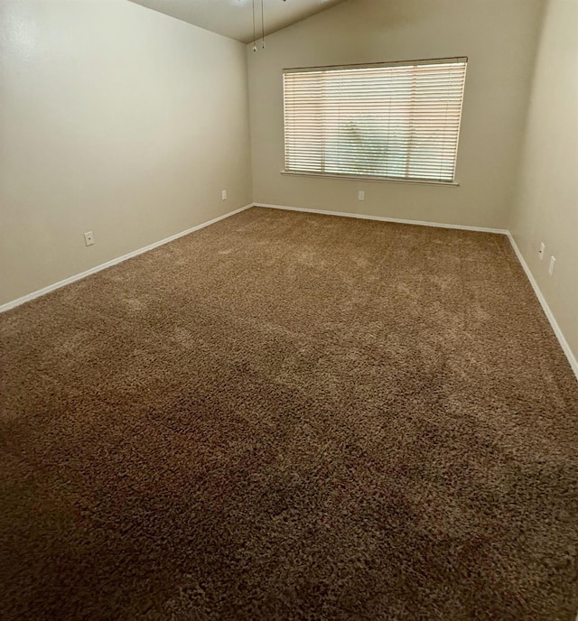 carpeted empty room featuring lofted ceiling, a ceiling fan, and baseboards