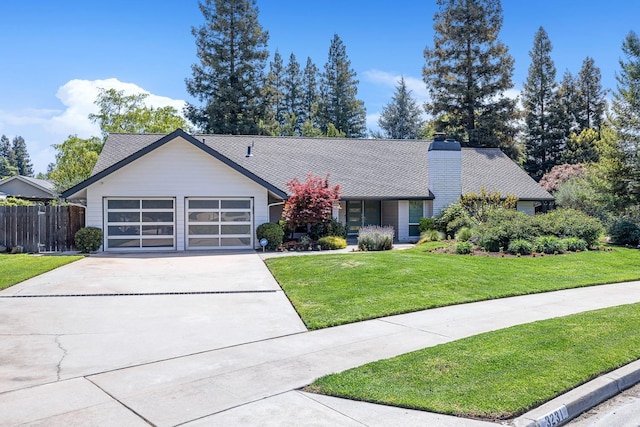 view of front of house with concrete driveway, a chimney, an attached garage, fence, and a front lawn