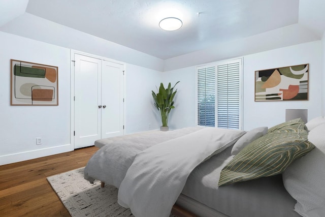 bedroom with wood finished floors, a closet, and baseboards