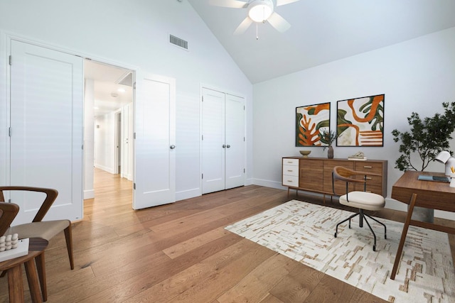 home office featuring wood finished floors, visible vents, a ceiling fan, and high vaulted ceiling