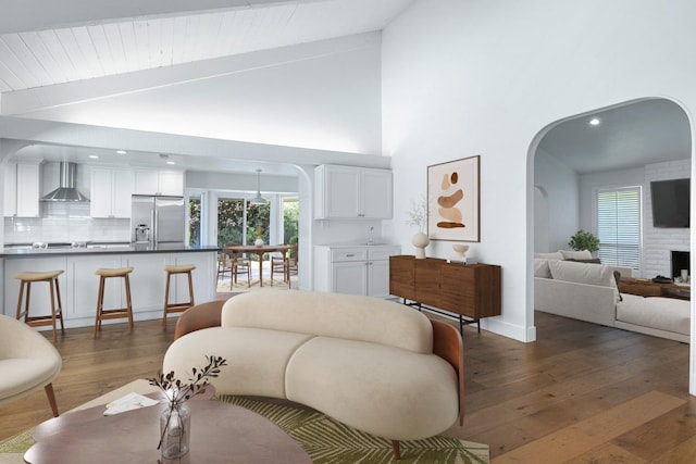 living area with hardwood / wood-style floors, high vaulted ceiling, recessed lighting, and arched walkways