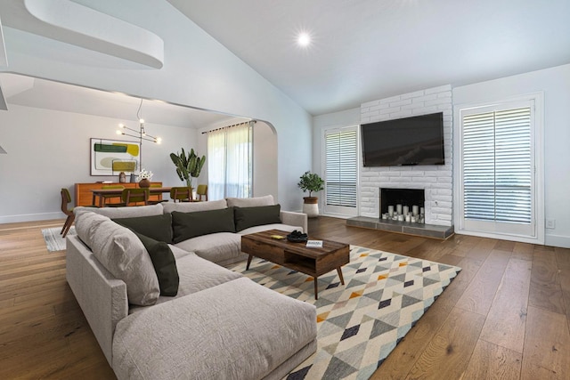 living room with hardwood / wood-style floors, baseboards, a notable chandelier, and high vaulted ceiling